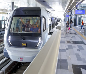 Modern LRT train arriving at Kepong station in Kuala Lumpur with passengers boarding on the platform