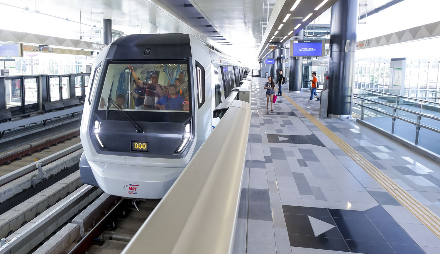 Modern LRT train arriving at Kepong station in Kuala Lumpur with passengers boarding on the platform